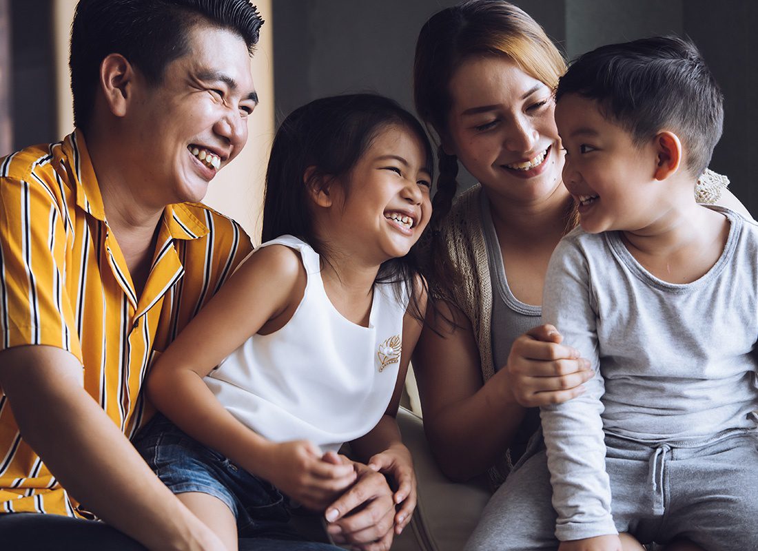 Personal Insurance - Closeup Portrait of Smiling Parents Having Fun Spending Time Together with Their Two Children at Home